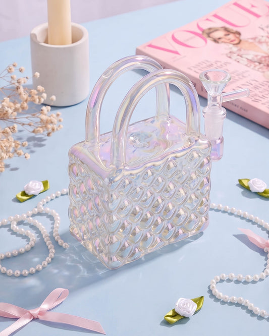 Iridescent handbag-shaped glass bong with quilted detailing, double handles, and a 14mm bowl surrounded by pearls, bows, and small flowers.